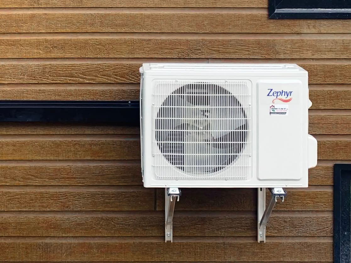 Zephyr outdoor air conditioning unit installed on a wood-clad wall.