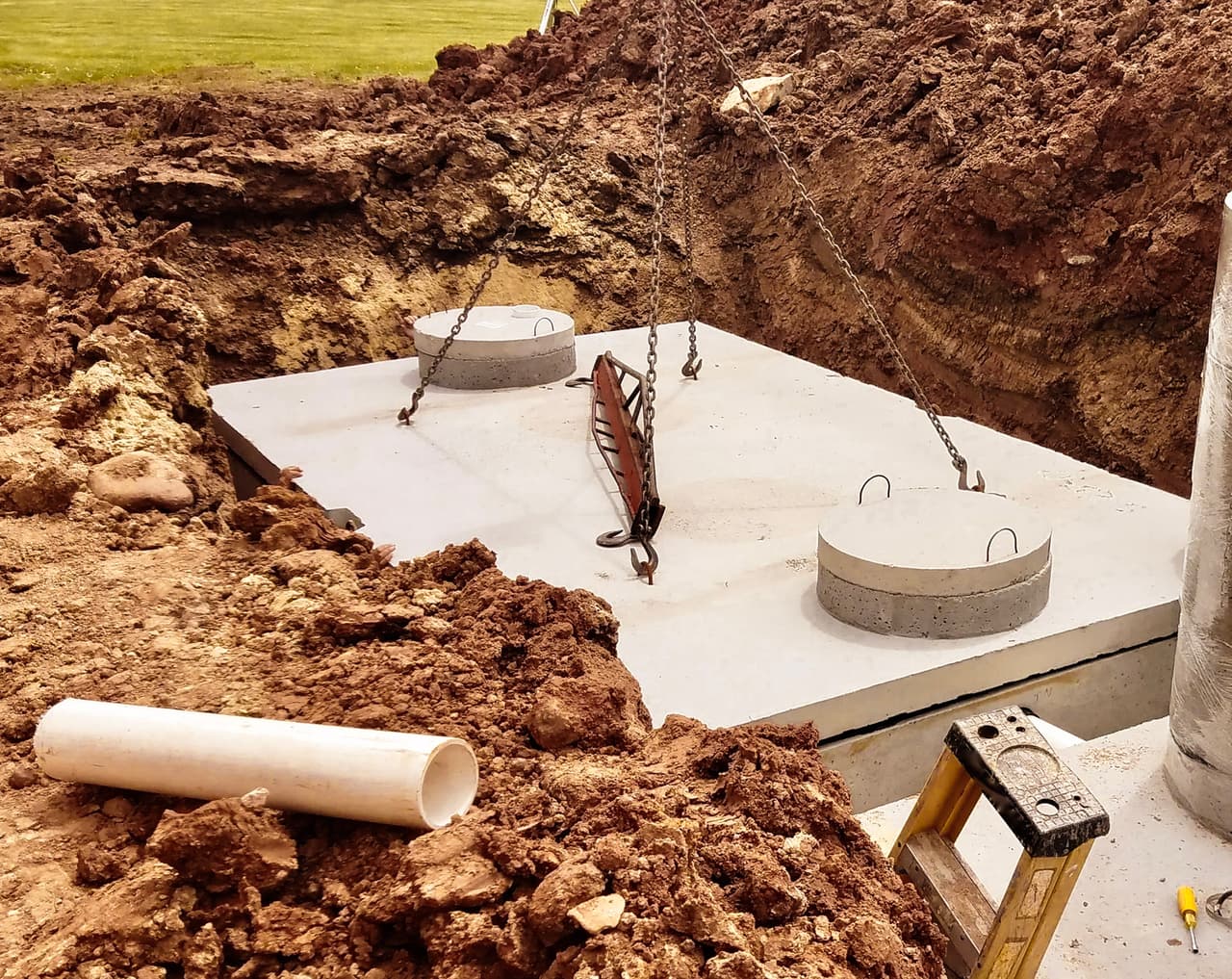 Concrete septic tank installation with precast slab in a residential excavation site.