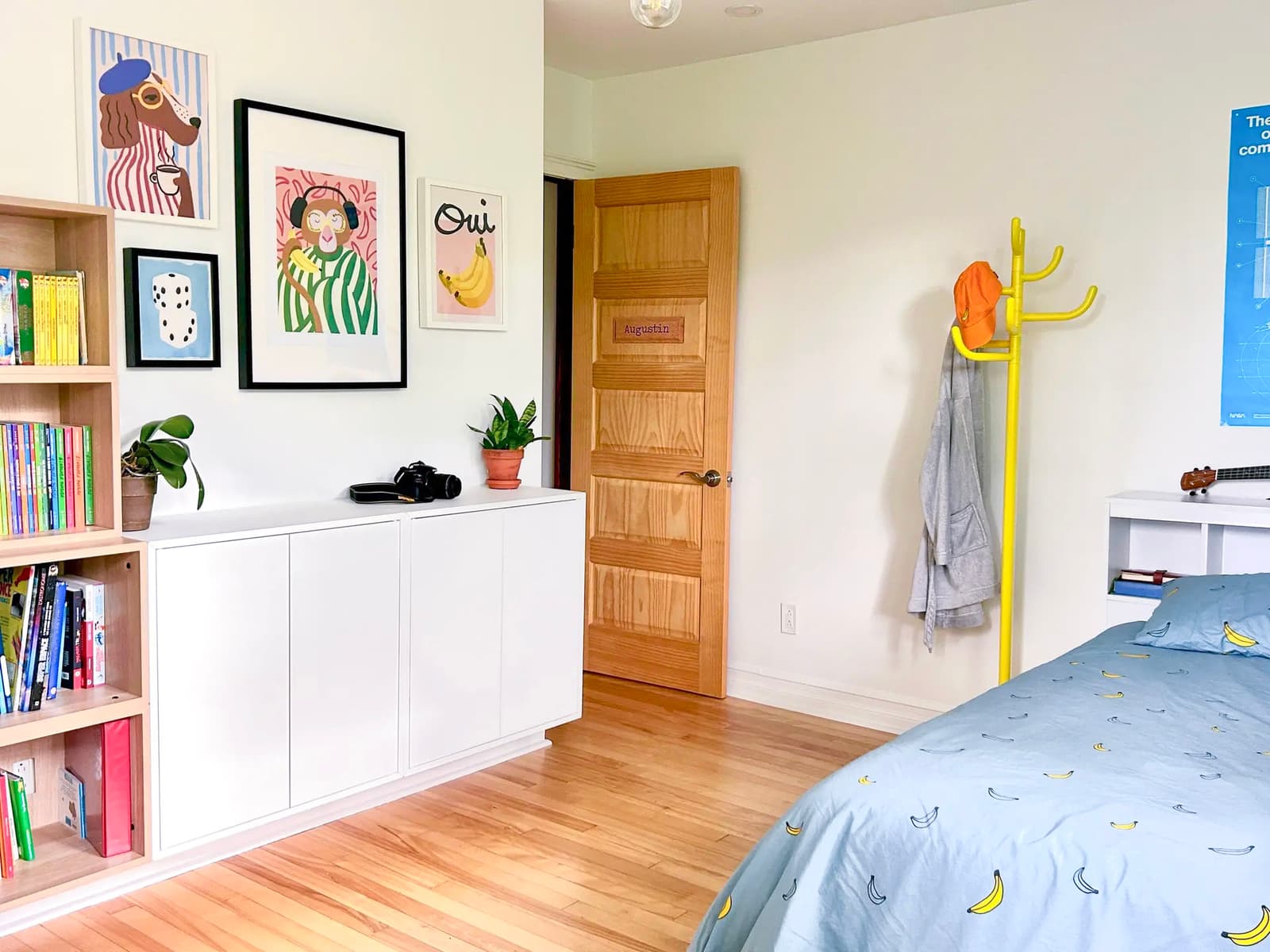 Children's bedroom with colorful decor, light wood flooring, and banana-pattern bedding.