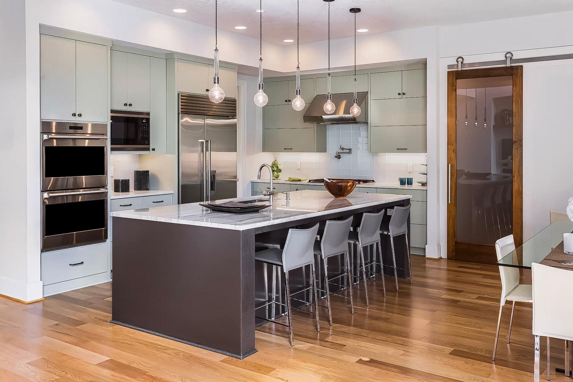 Modern kitchen with central island, marble countertop, and stainless steel appliances.