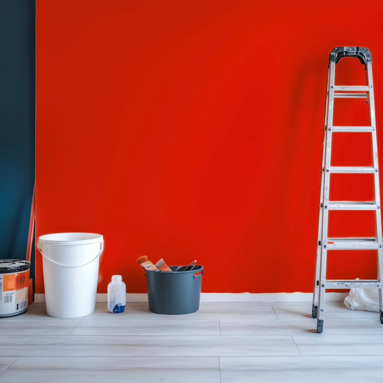 Bright red wall being painted with bucket, paintbrushes, and stepladder on light wooden floor