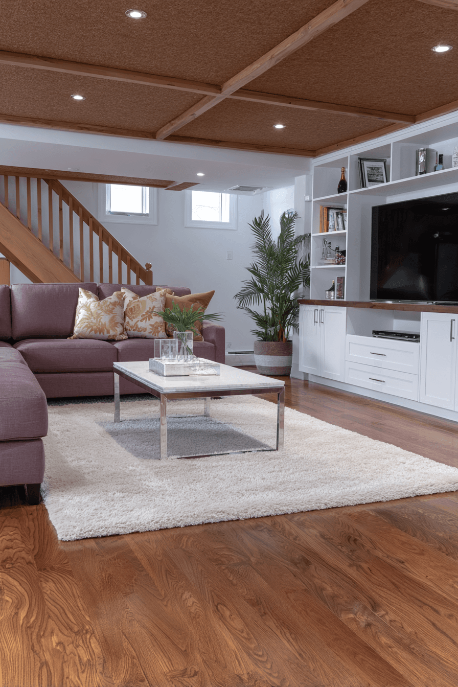 Modern finished basement with wood ceiling, cozy sofa, built-in TV unit and hardwood flooring