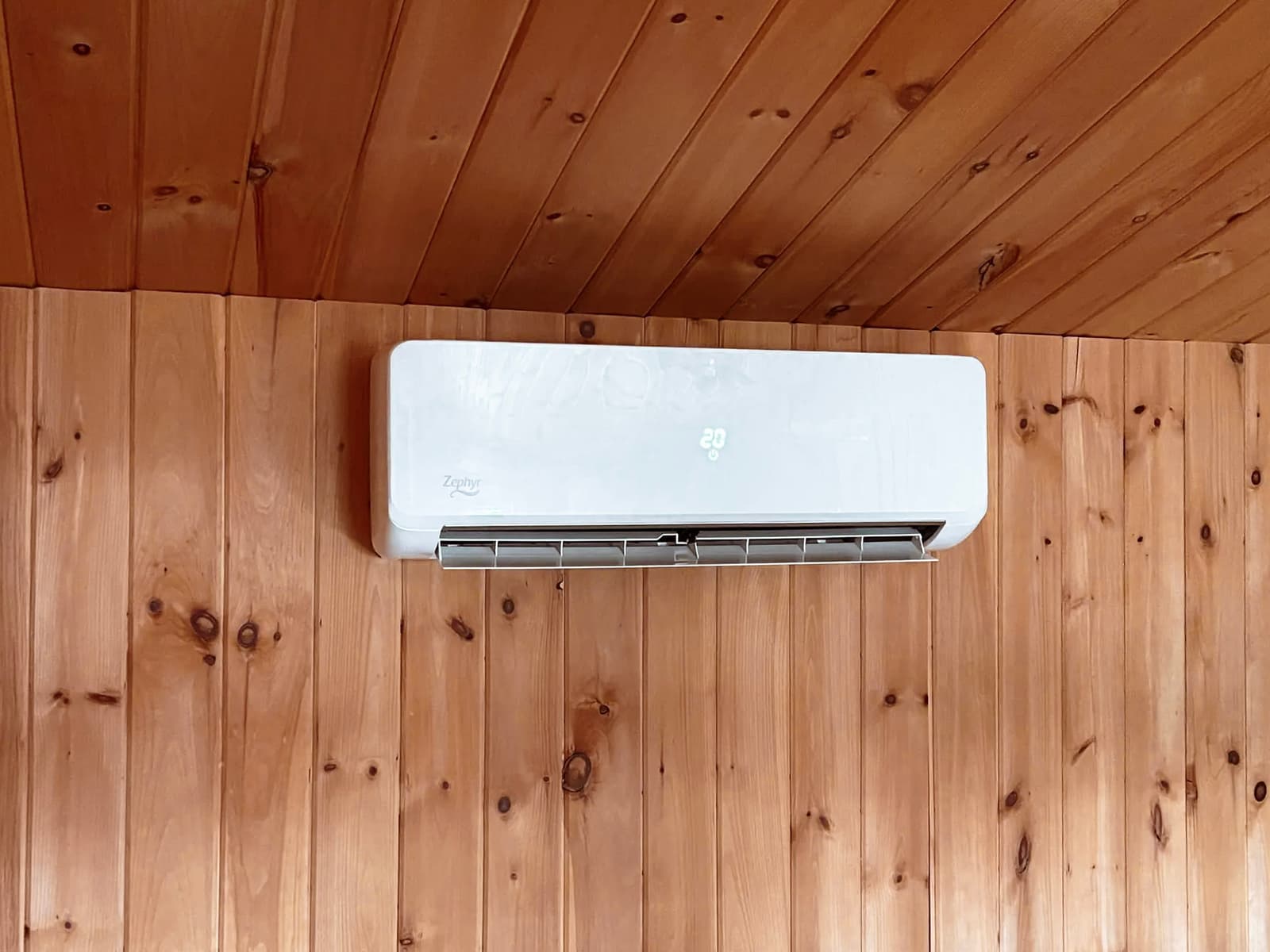 Zephyr wall-mounted air conditioner on a wooden wall, providing thermal comfort in a rustic home.