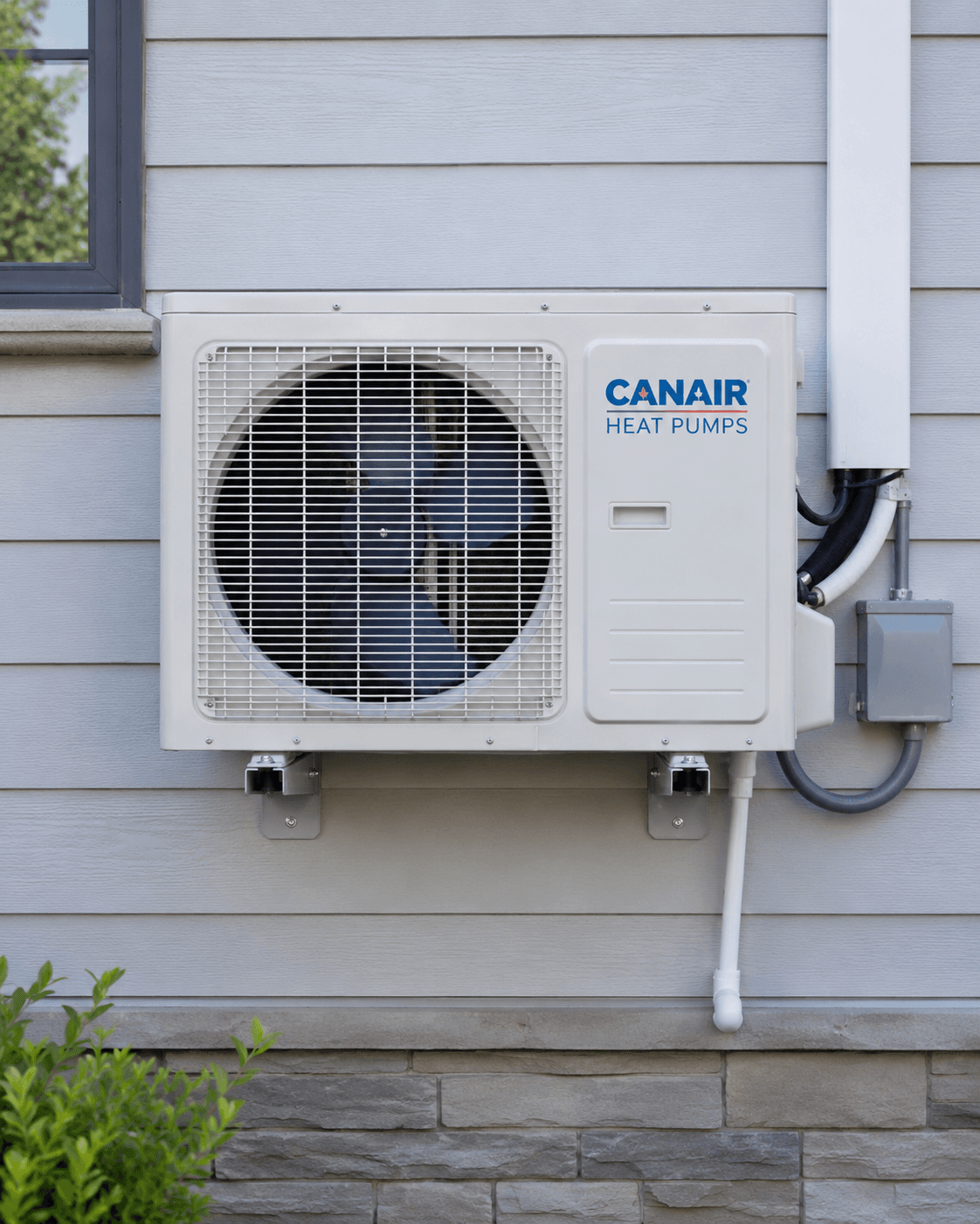 Canair outdoor heat pump installed on a gray residential wall, with fan grille, visible conduits and mounting brackets.