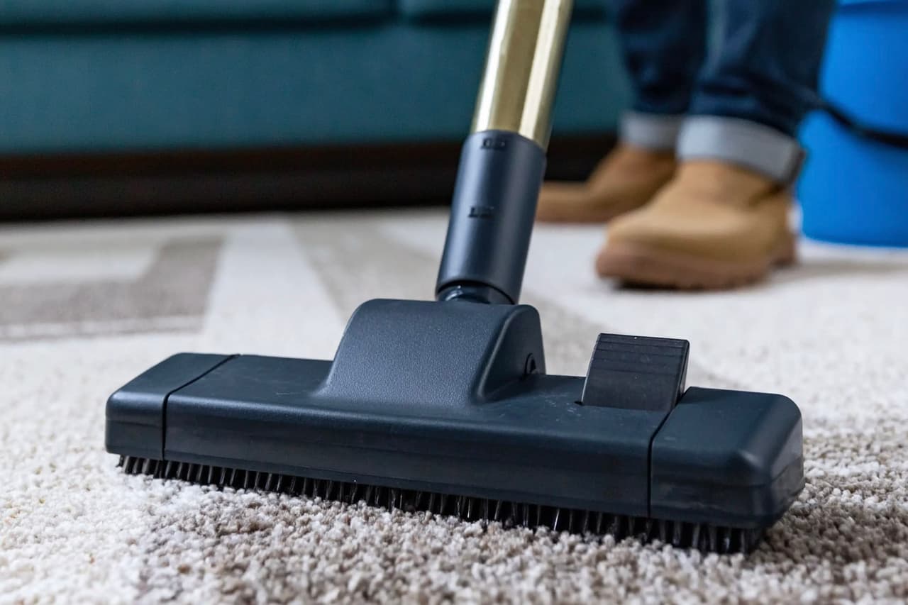 Deep cleaning of a residential carpet with a vacuum cleaner equipped with a brush for interior home maintenance.