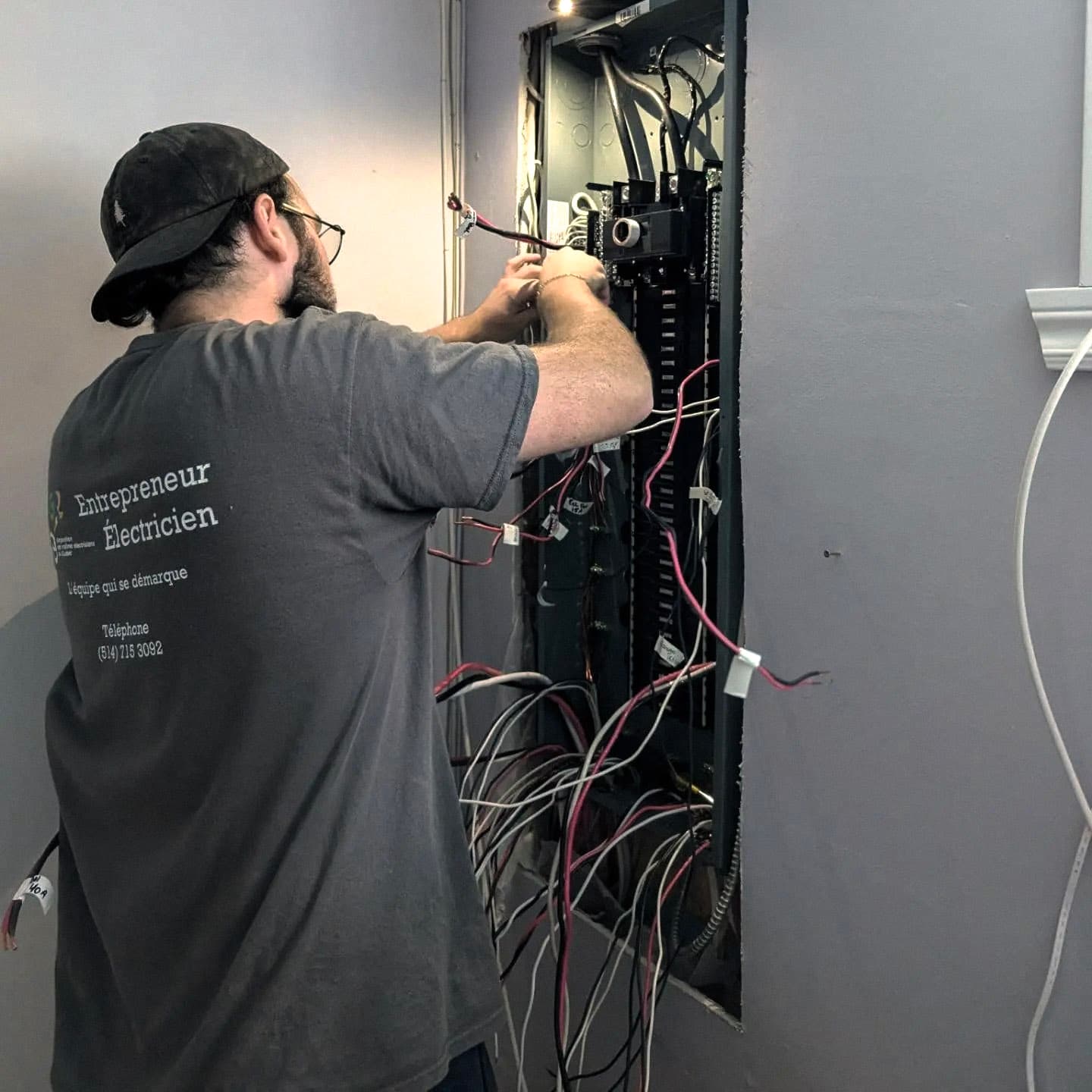 An electrician performing repairs on a residential electrical panel with exposed wiring.
