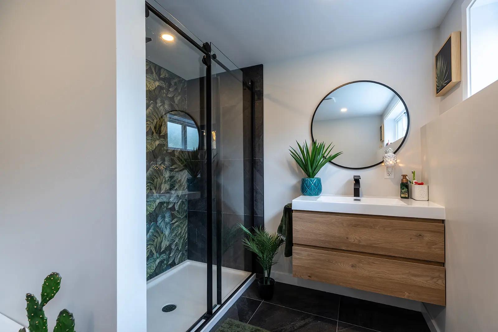 Modern and bright bathroom with a walk-in shower, wooden vanity, and green plants.