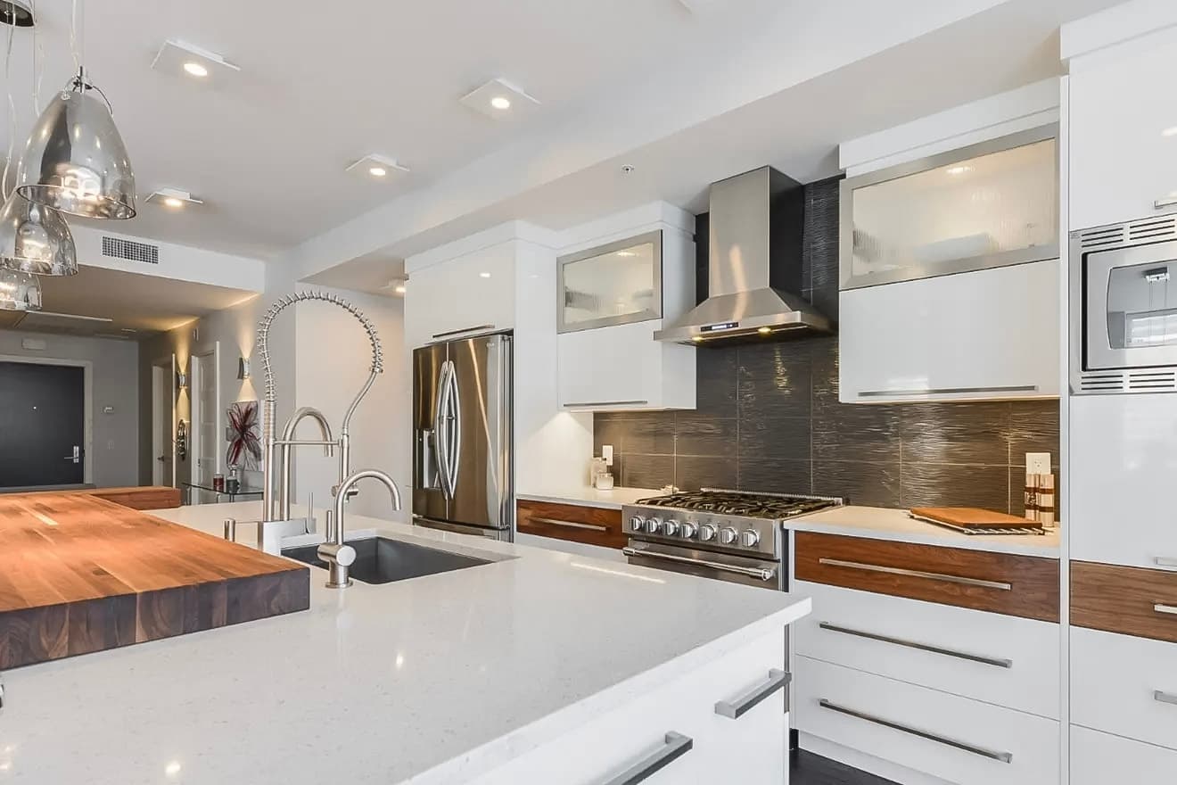 Modern kitchen with a central quartz island, stainless steel appliances, and hanging lights for a sleek and contemporary design.