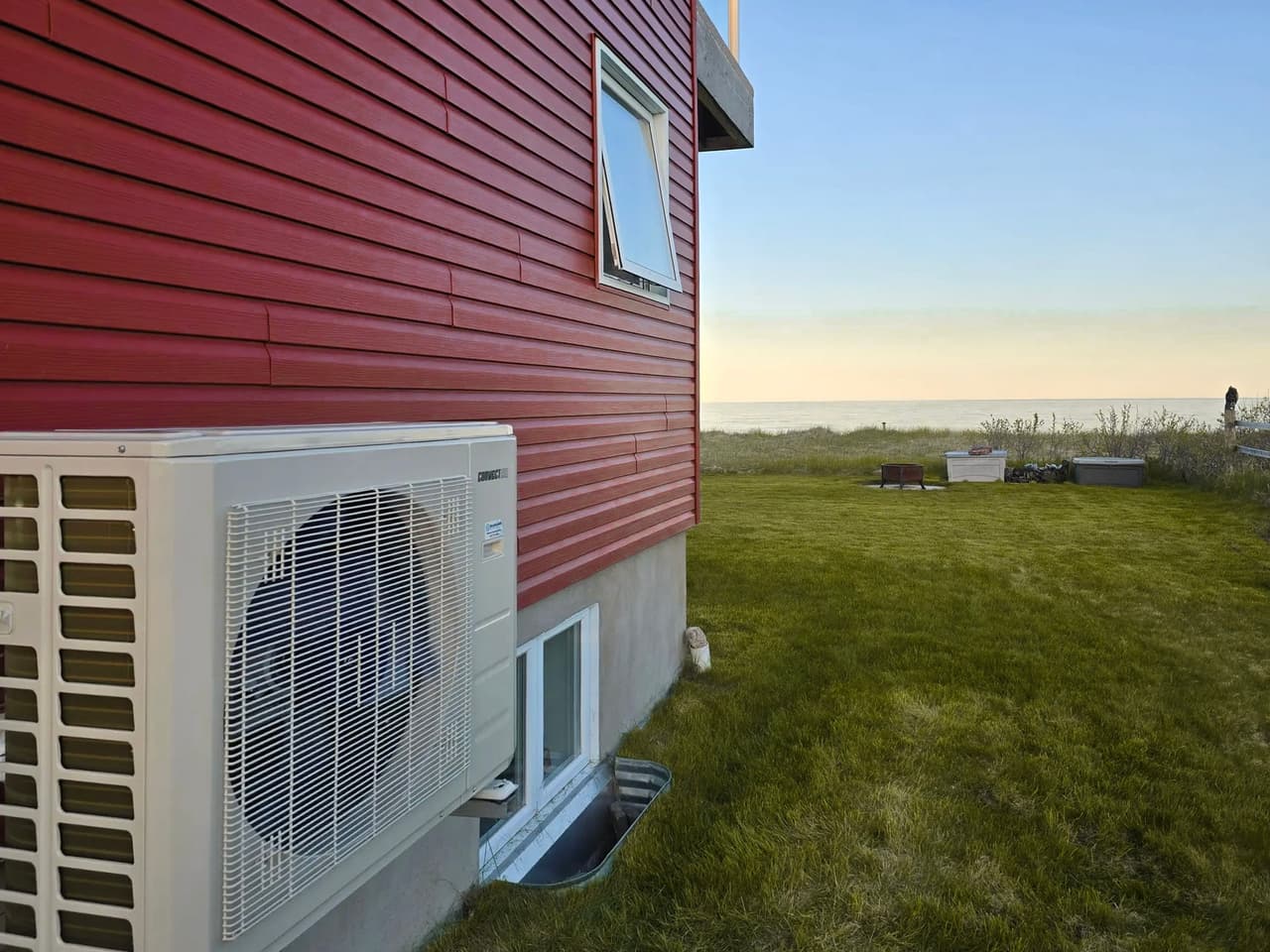 Samsung outdoor air conditioning unit with a fan, facing a lush garden and the  ocean.