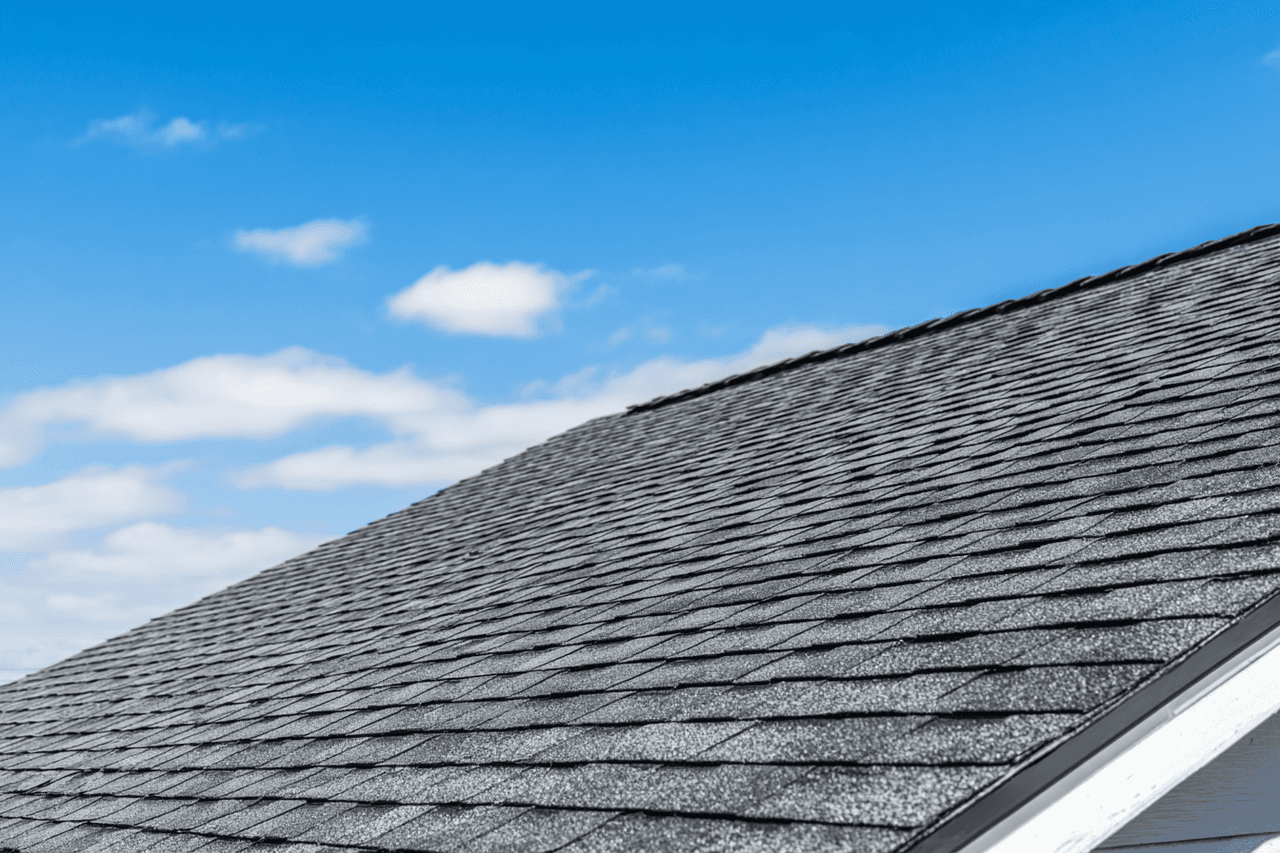 Gray asphalt shingle roof under a blue sky with some clouds