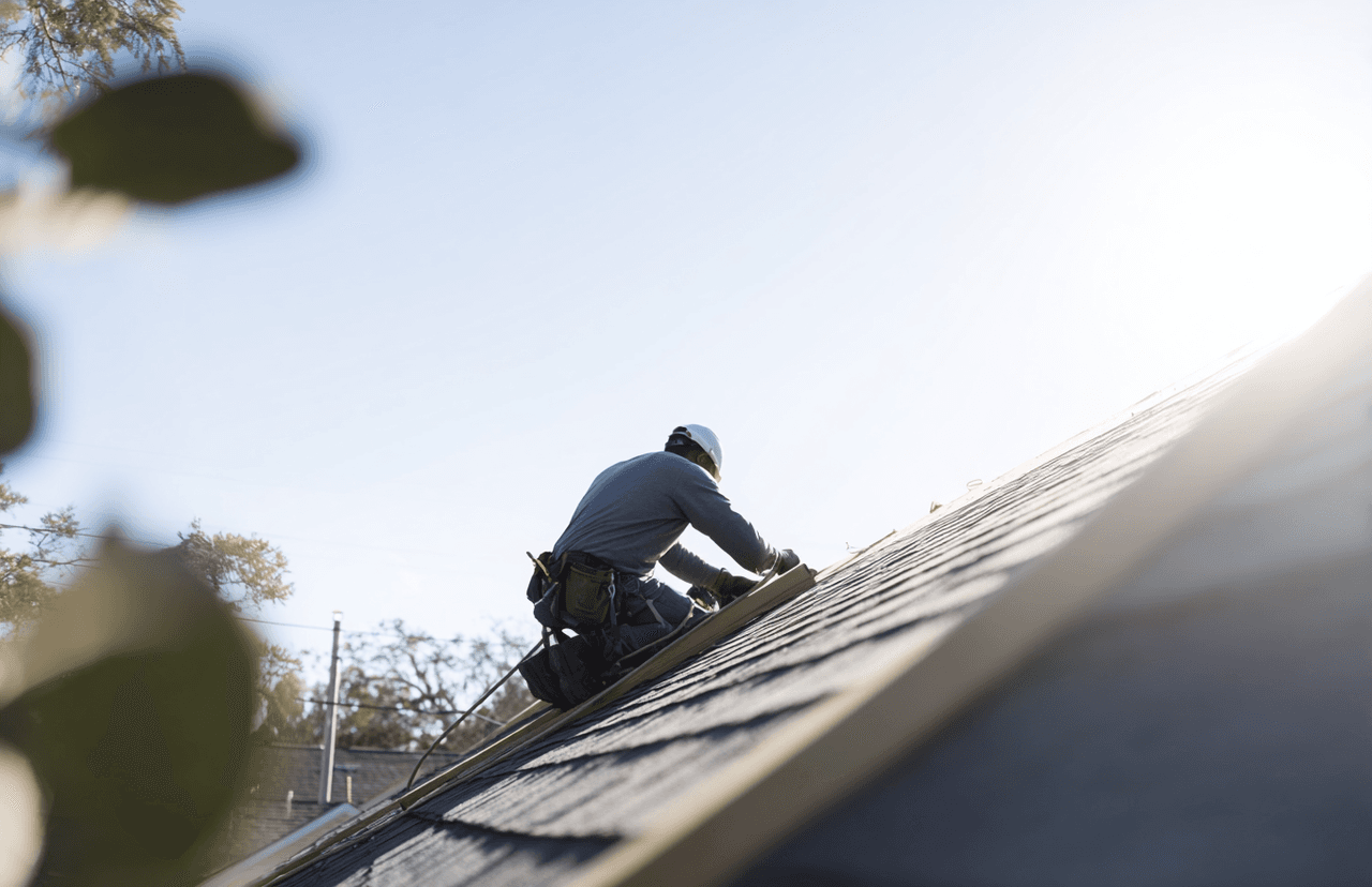 Worker wearing safety helmet working on a house roof under a sunny sky