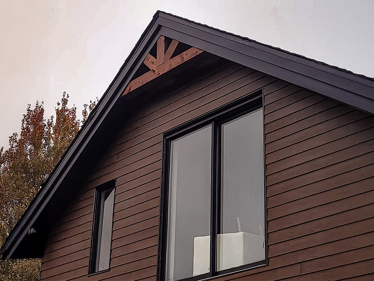 Modern facade with wood siding, large windows, and exposed framework.
