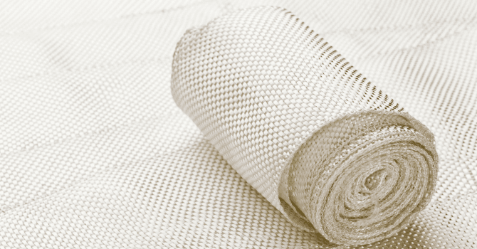 Roll of white insulating fabric or fine mesh material shown in close-up on a similar textile surface.