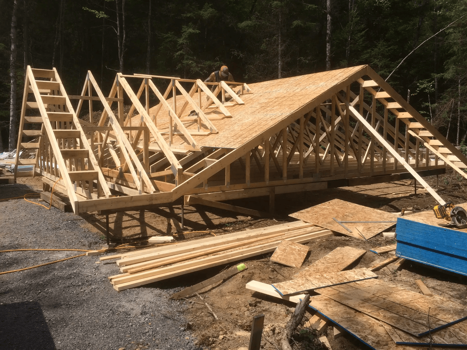 &nbsp;Wooden house frame construction with roof sheathing installation in a forested area