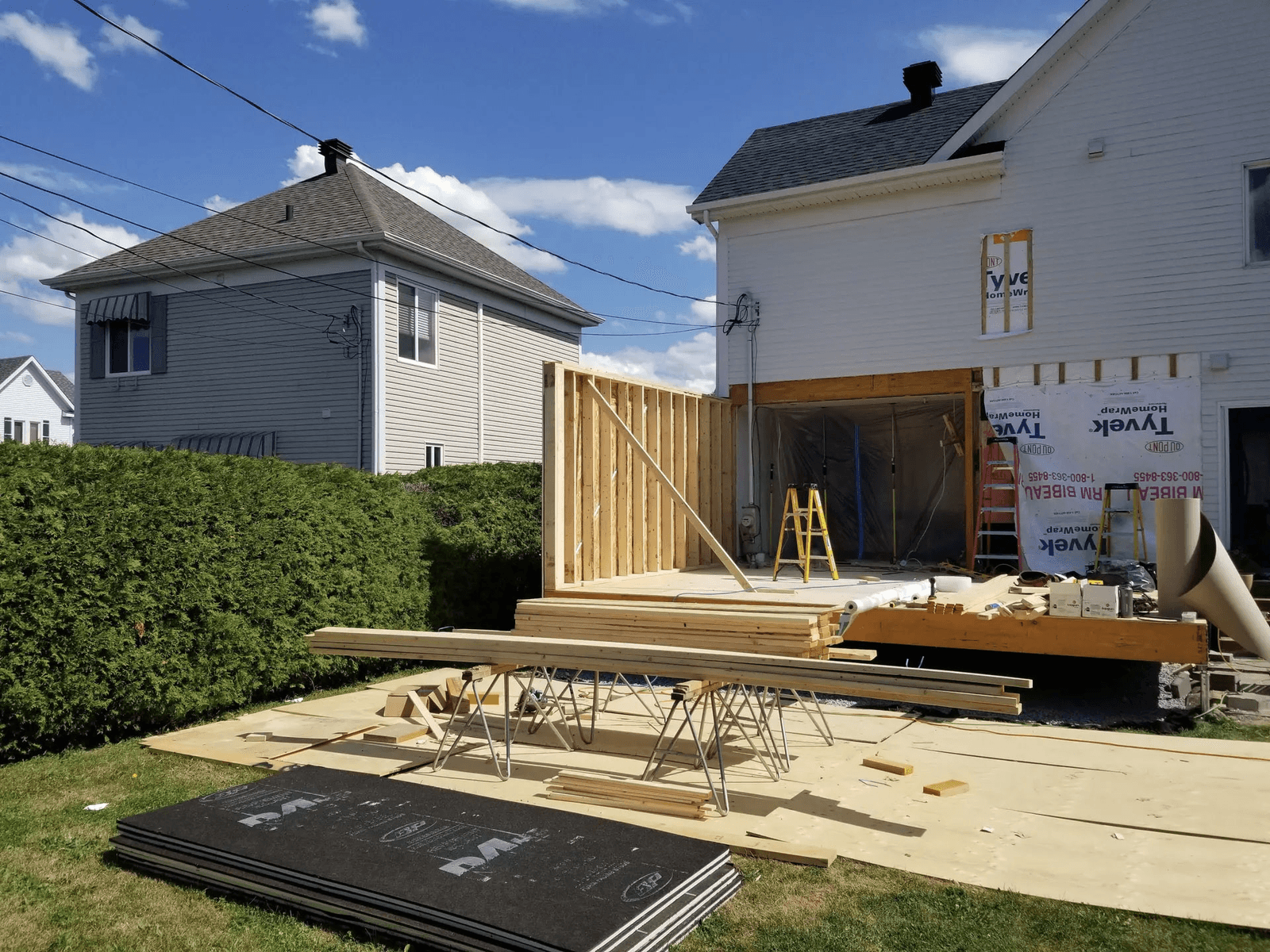 Residential home extension under construction at the rear of a house with timber framing, new structural deck and walls being assembled.
