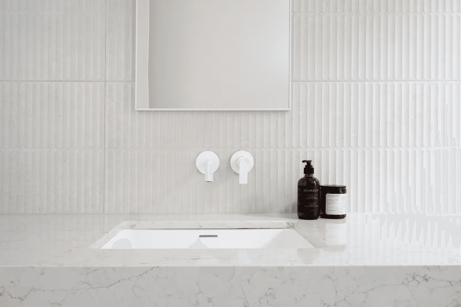 Minimalist bathroom with a modern inset sink, white wall-mounted faucets, and textured wall tiles.