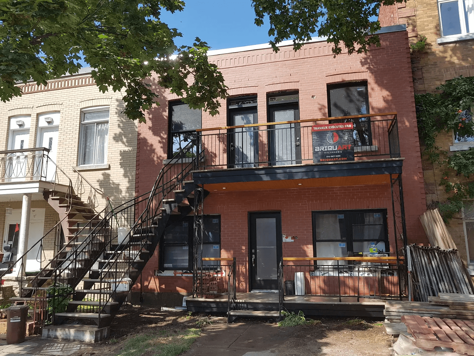 Red brick facade renovation of a two-story residential building featuring black metal exterior staircases, balconies, modern doors and windows