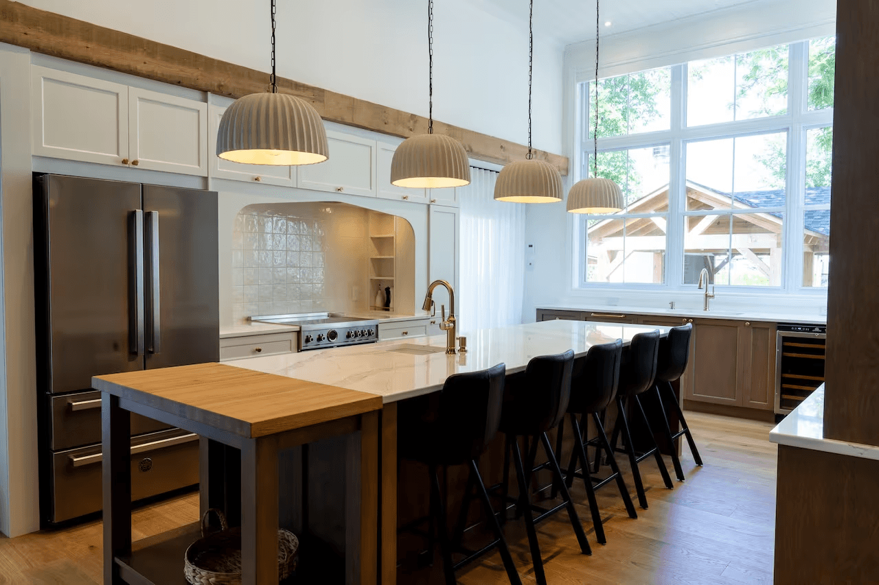 Modern kitchen with a large central island, white and wood cabinetry, stainless steel refrigerator, pendant lighting and wood flooring