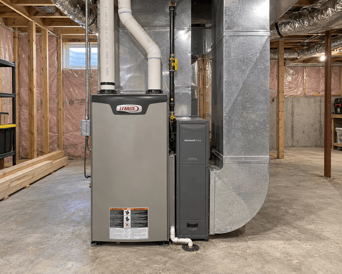 Unfinished basement with residential furnace, central heating system, metal ventilation ducts, piping and exposed wall insulation.