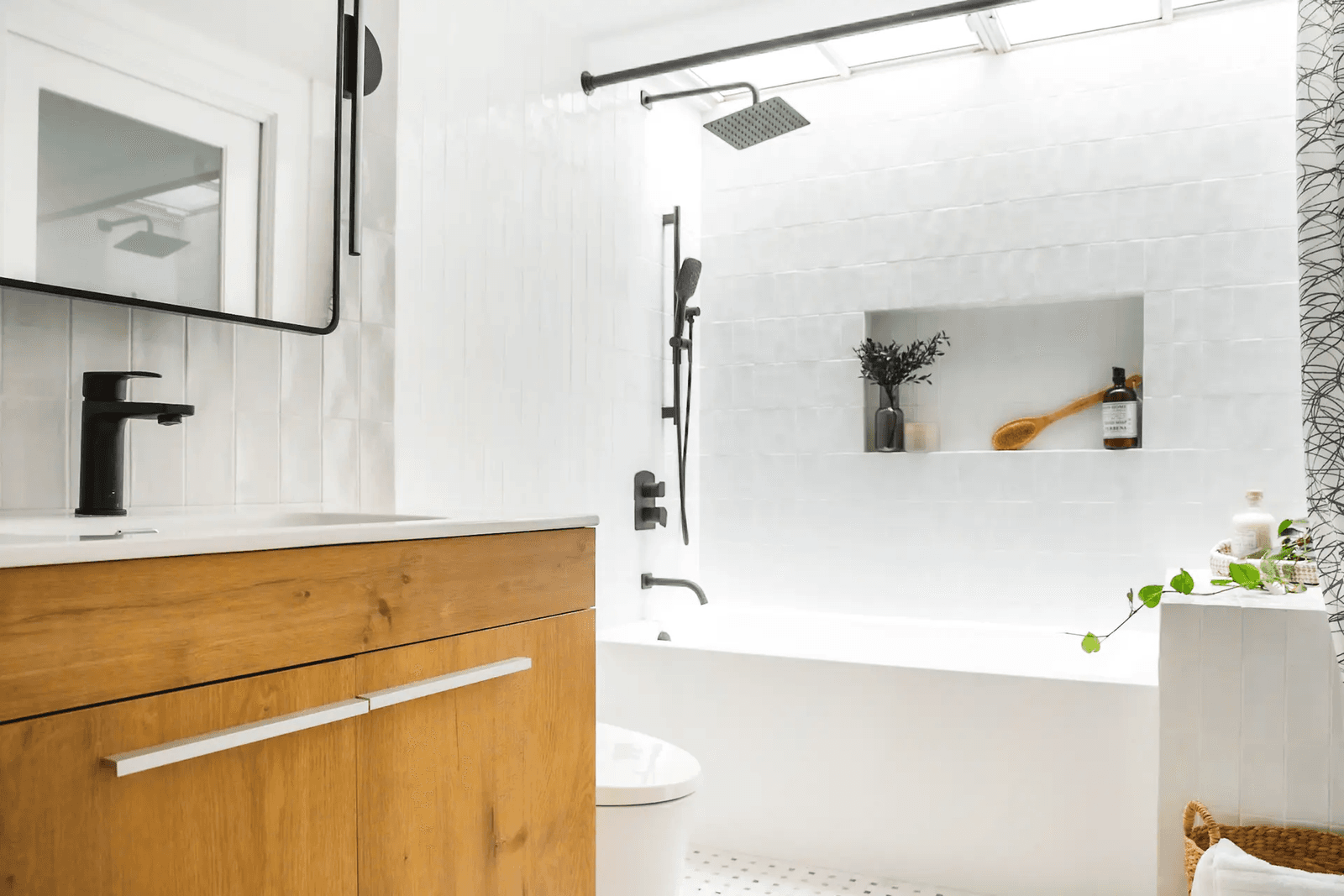 Bright bathroom featuring a white bathtub, a rainfall showerhead, and a wooden vanity.
