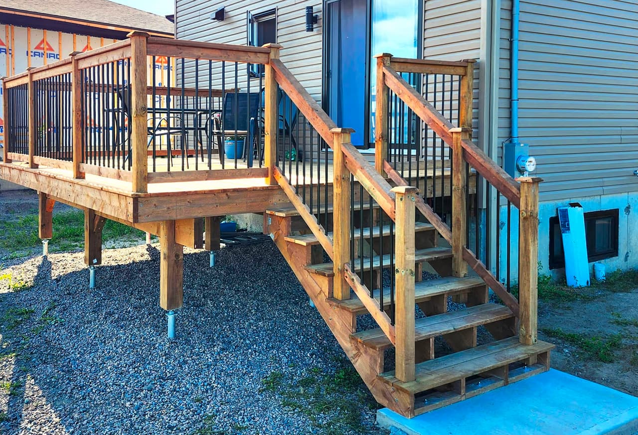 Wood deck with stairs, black railings and exterior siding on a residential house