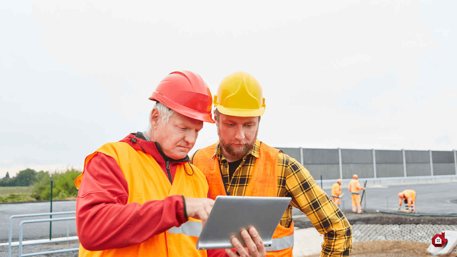 two men in front of a computer on a construction site