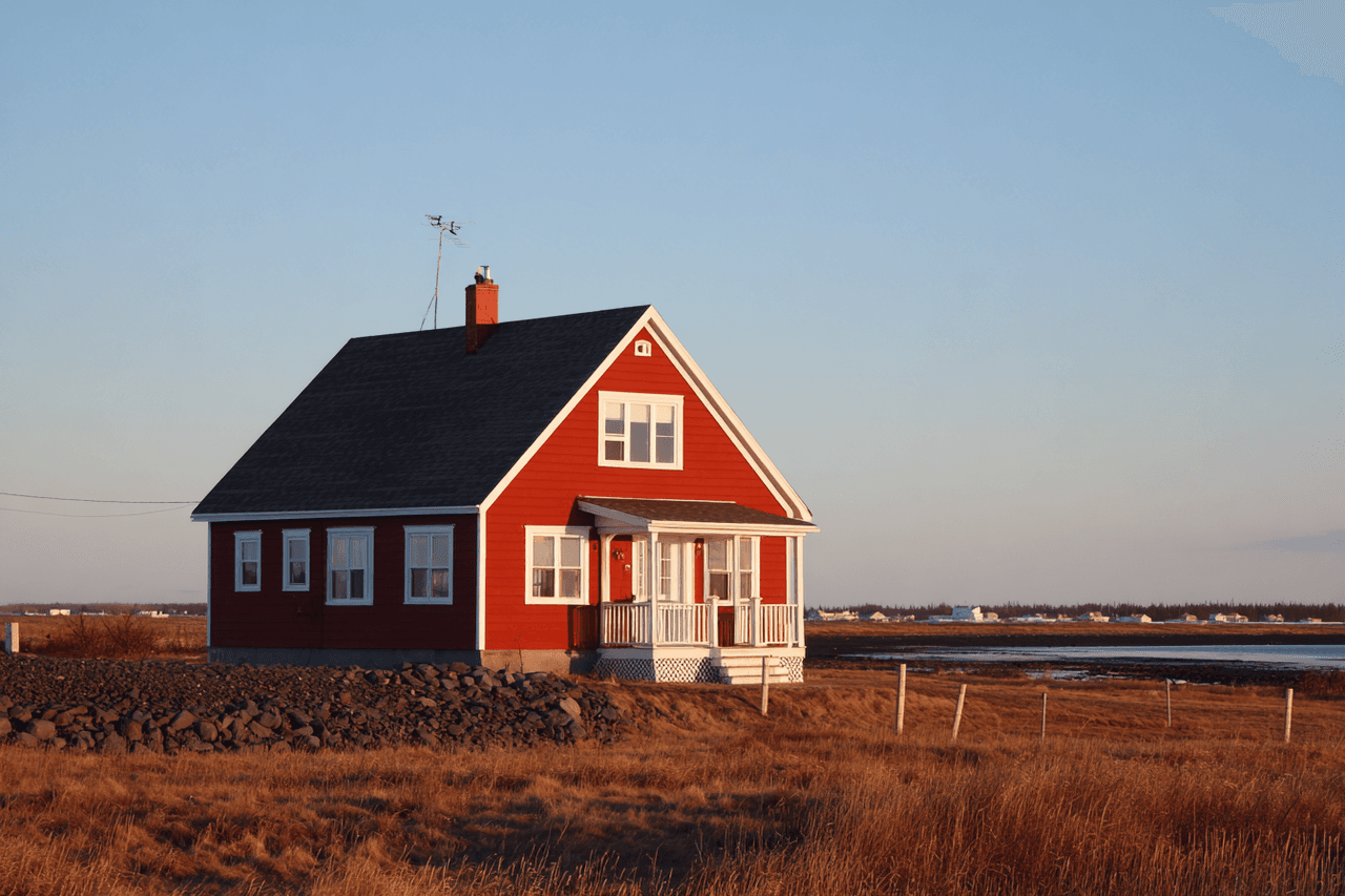 Traditional red wooden house with a sloped roof, located in the countryside near the water