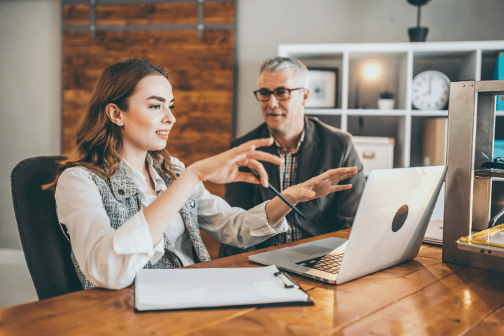 a man and a woman in front of a computer talking 