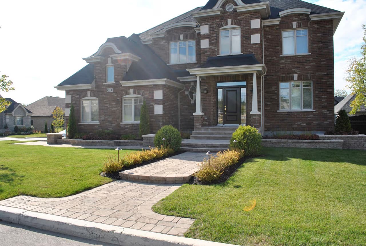Large brick residence with landscaped front yard, interlocking pavers and elegant main entrance.