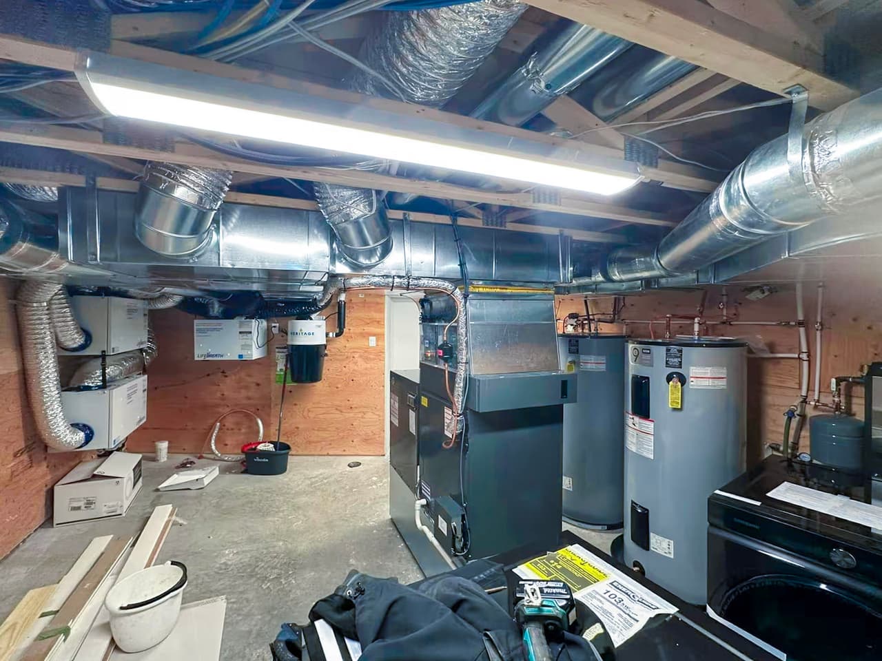 Basement mechanical room with furnace, water heater, ventilation ducts and residential heating equipment