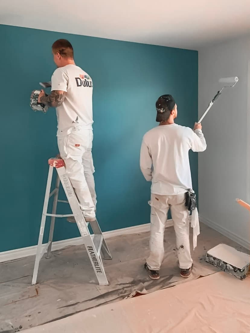 Interior painting work by professional painters applying blue paint on a wall for a modern renovation.
