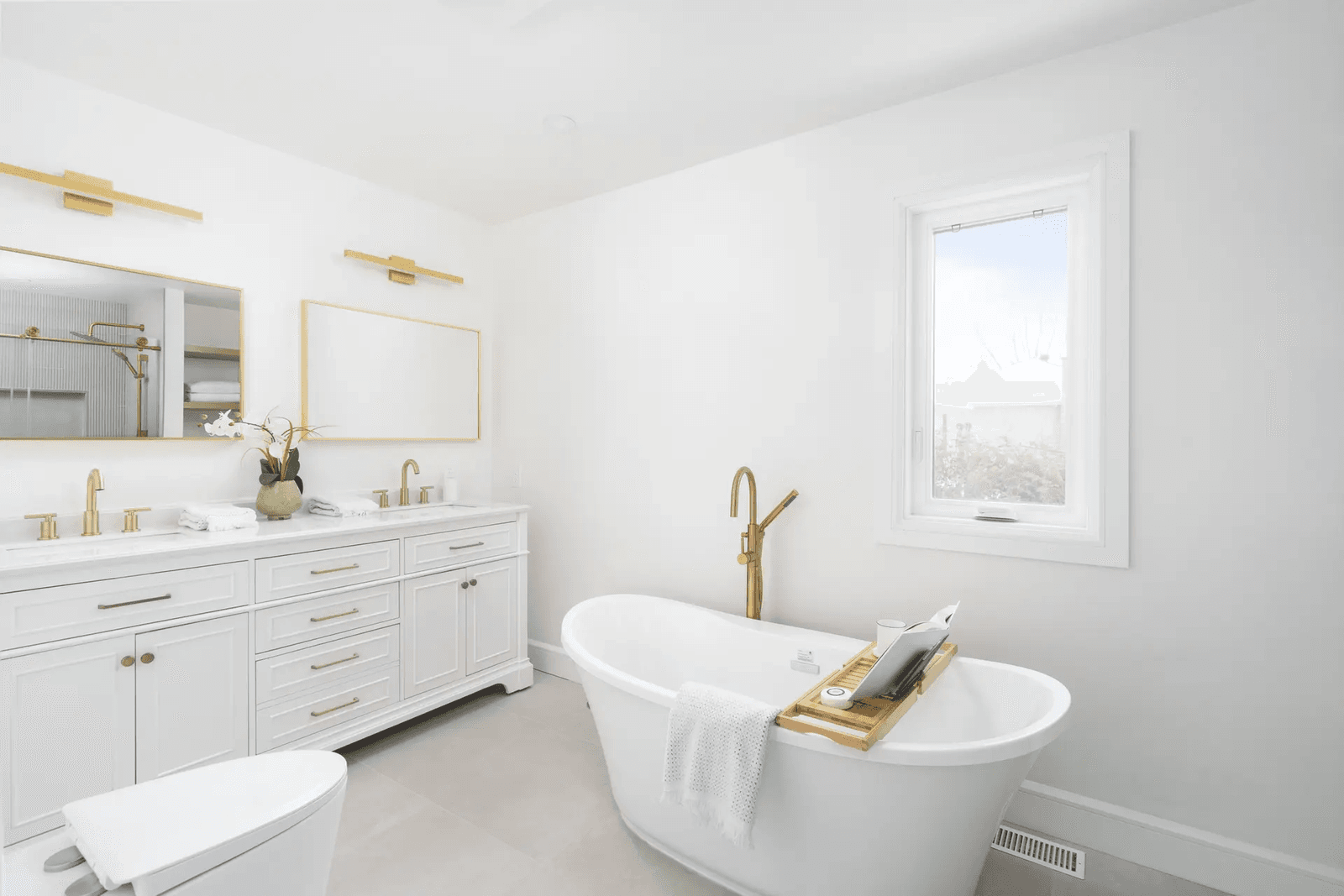 Bright, modern bathroom with a freestanding bathtub and brass finishes.