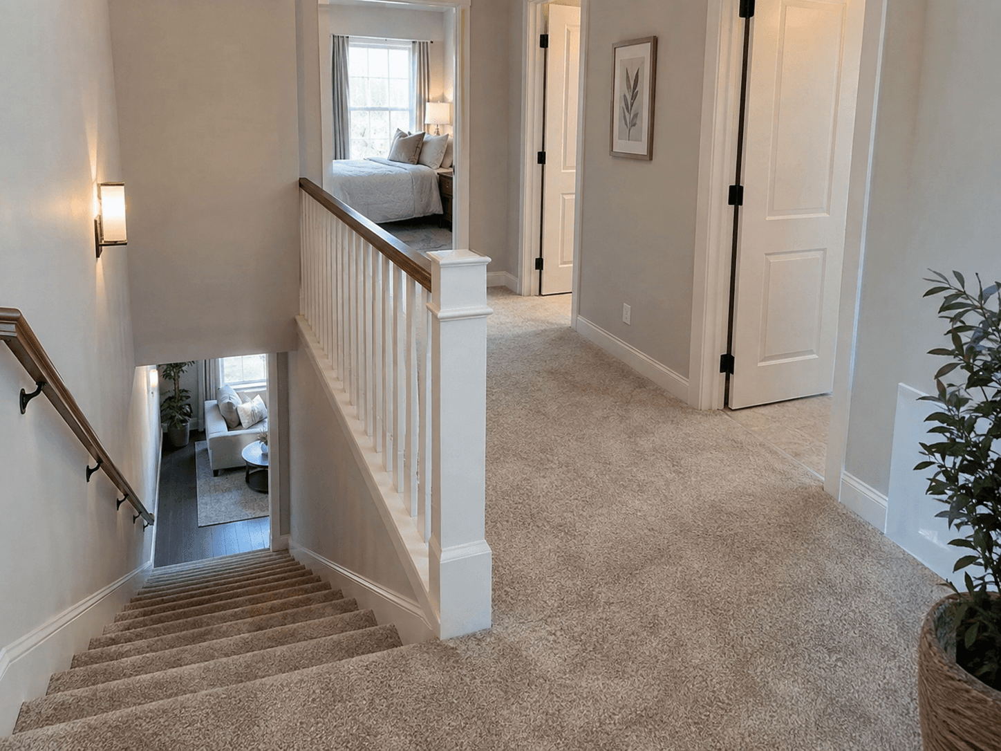 Bright upstairs landing with beige carpeted staircase, white railing with wooden handrail, white interior doors, and access to bedrooms.