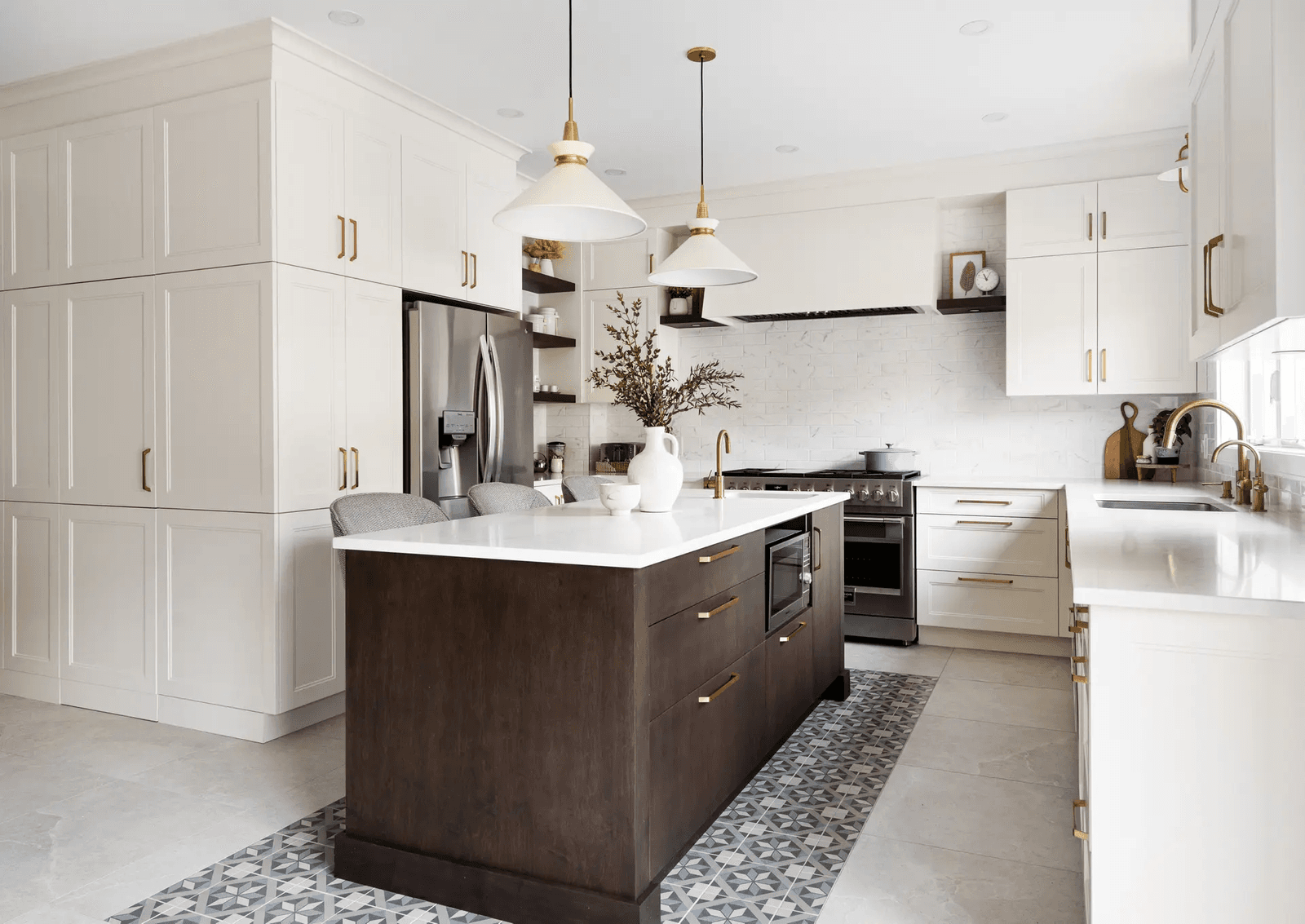 Transitional-style kitchen in Montreal featuring a dark wood central island with warm-toned drawers and a white quartz countertop. White Shaker cabinets and gold handles add an elegant touch, while geometric ceramic flooring gives the space added character.