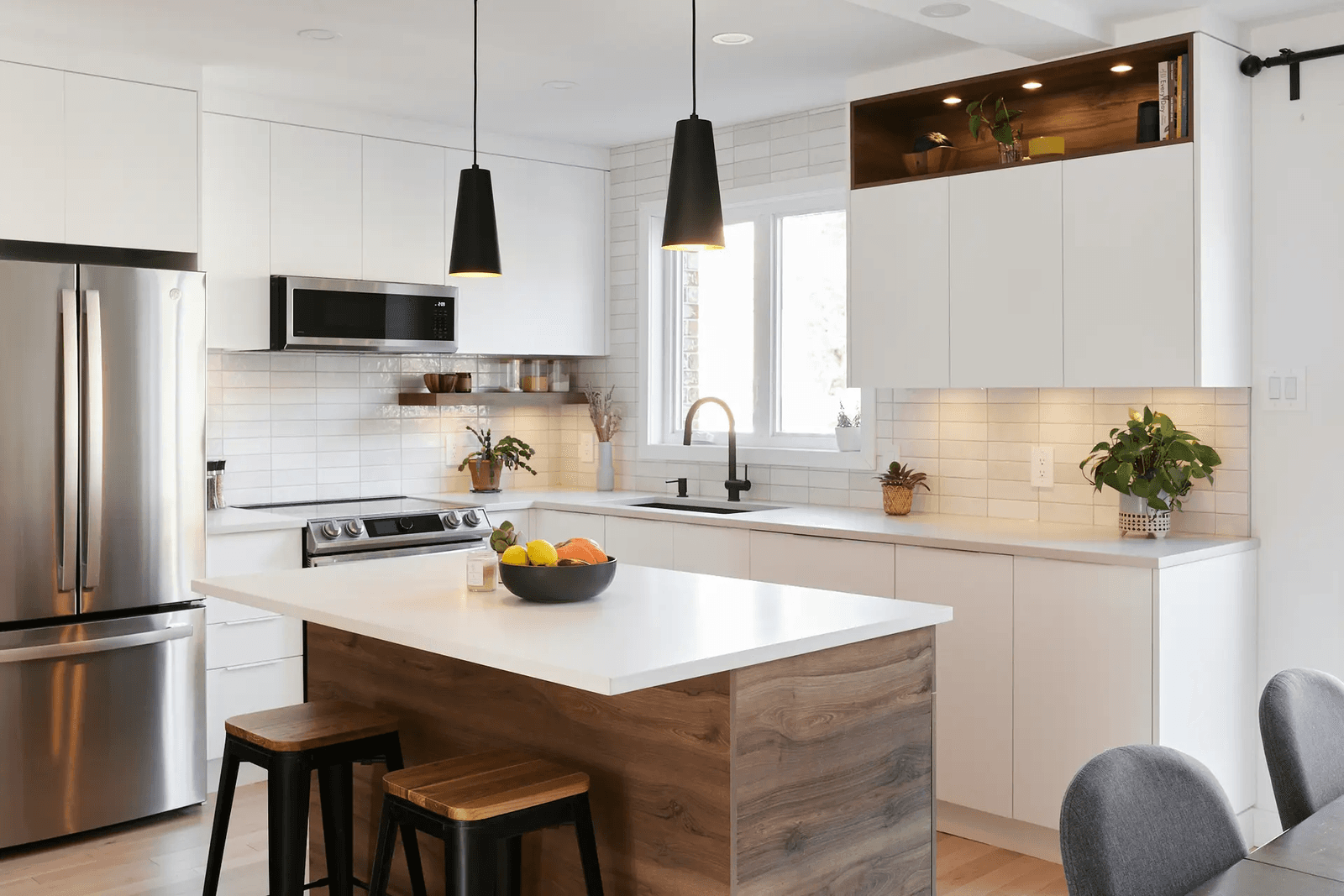 Scandinavian-style kitchen in Montreal featuring a central island with a natural wood countertop, minimalist white cabinets and a white subway tile backsplash. Light wood flooring adds warmth to the space.