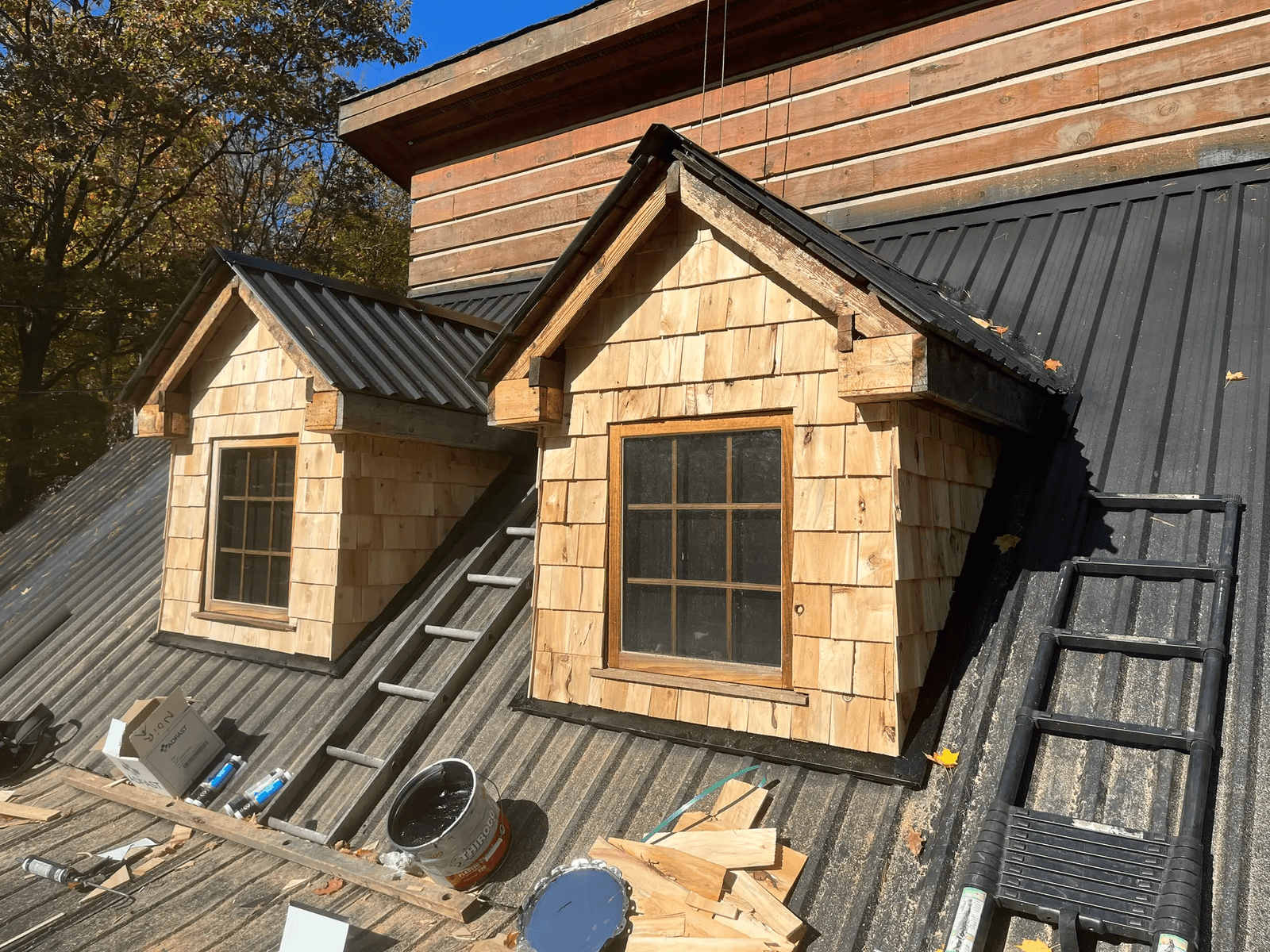 Wooden dormers on a black metal roof in a renovation project.