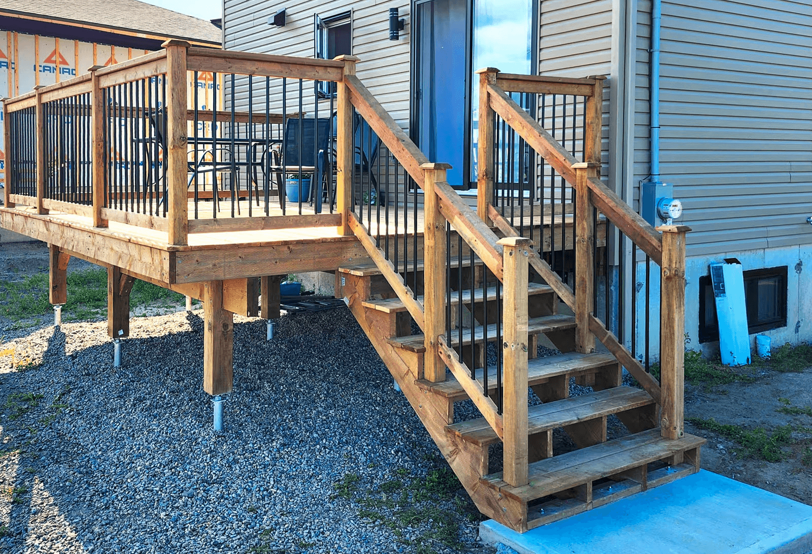 Wood deck with stairs, black railings, and residential home siding