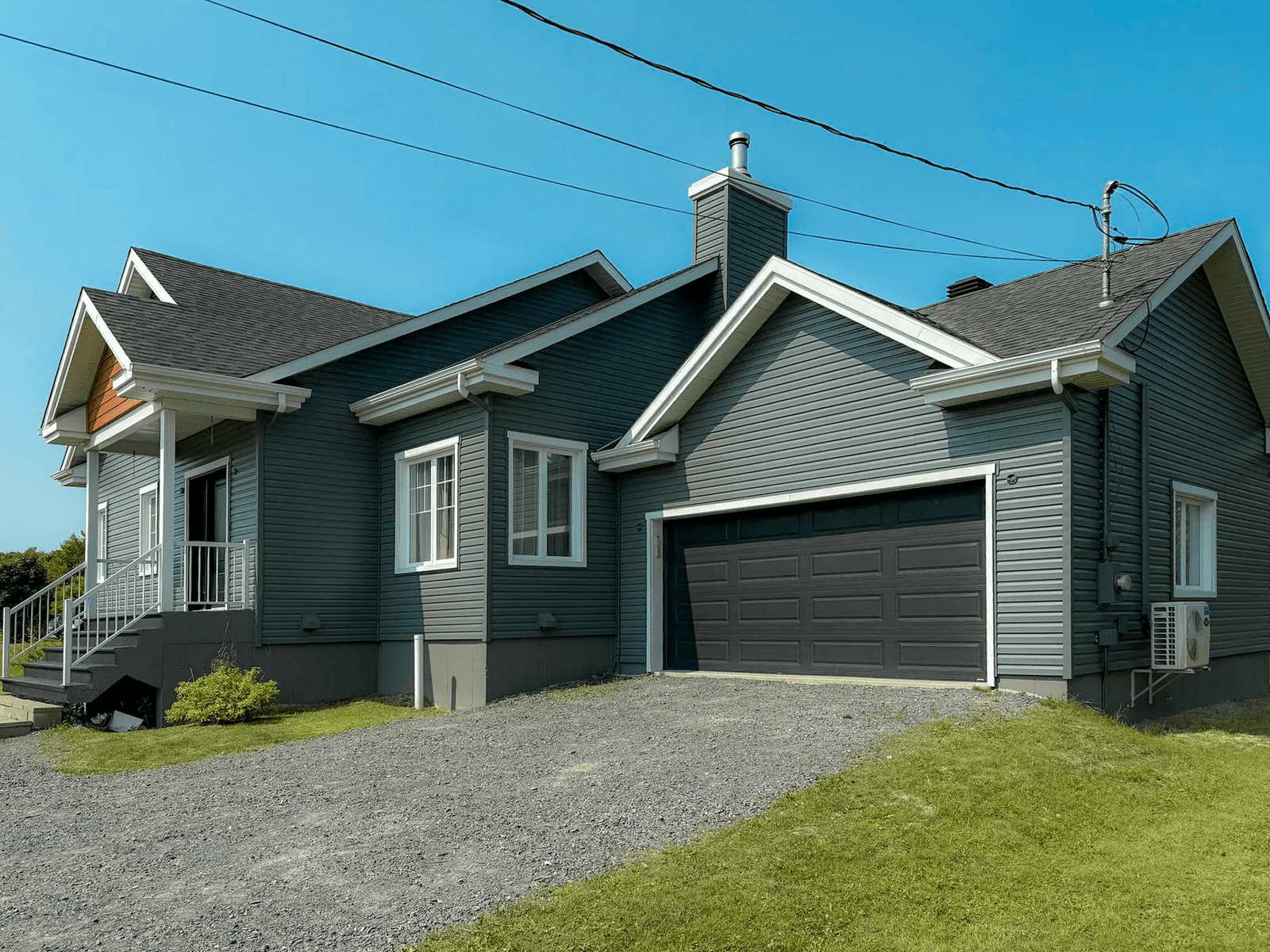 Modern single-family home with grey vinyl siding, double garage, and black shingle roof.