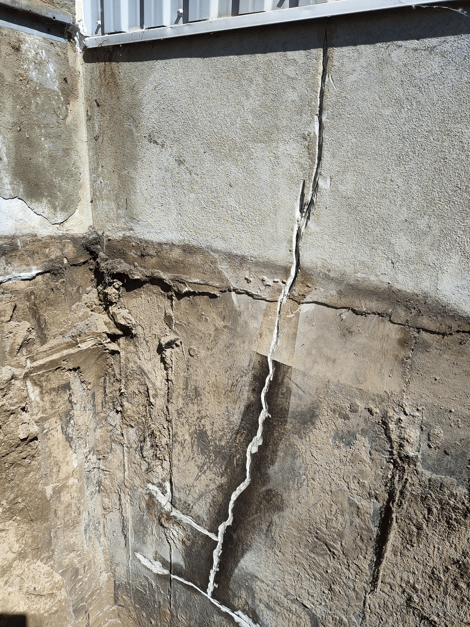 Major stair-step crack on a concrete foundation with visible injection repair