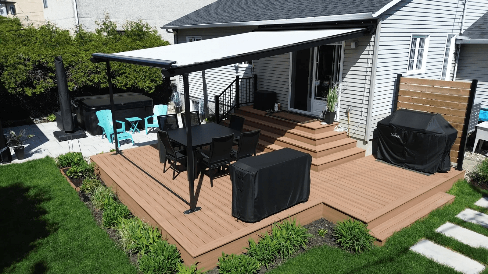 Composite deck with retractable awning, dining area, and outdoor hot tub.
