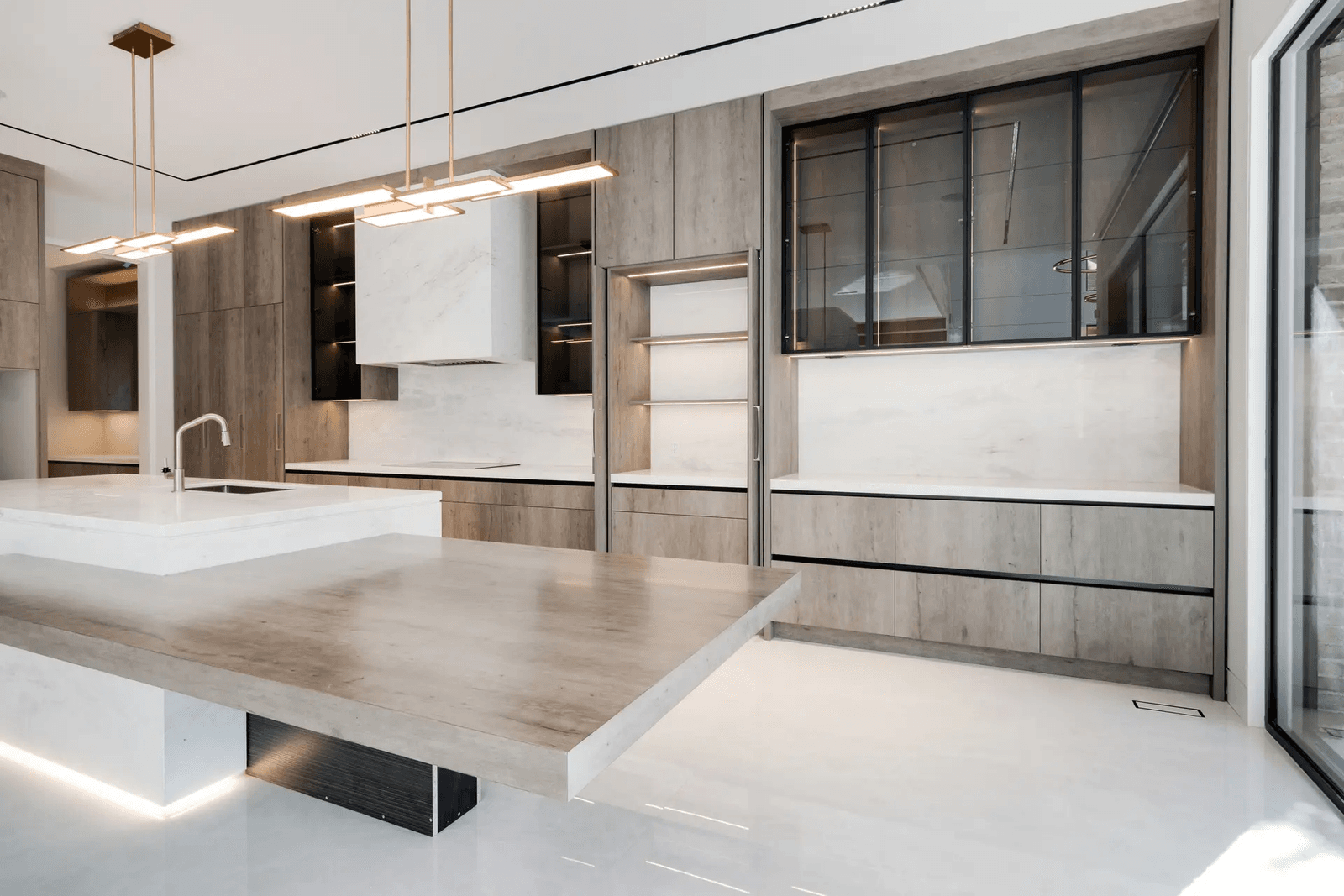 Modern and minimalist kitchen with a central island, wooden cabinets, stone countertop, and pendant lighting.
