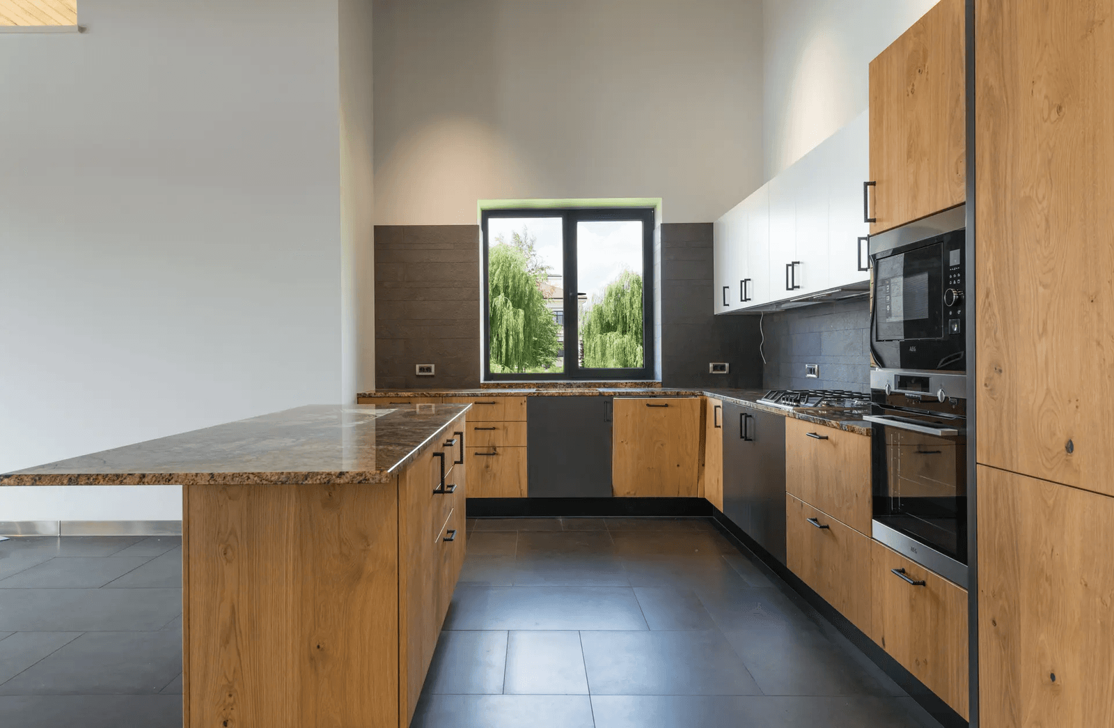 Modern kitchen with wooden cabinets, granite countertops, integrated appliances, and a large window providing a panoramic view.