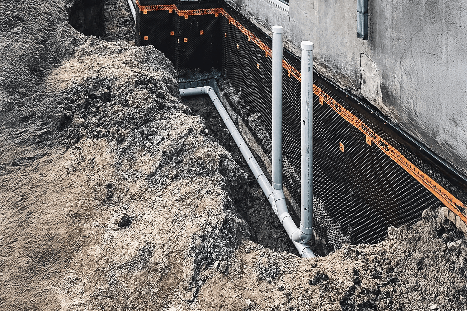 Excavation work, pre-foundation drain and waterproofing fabric installation around a house