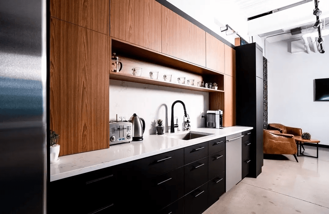 Contemporary kitchen with custom wood cabinetry, black cabinets, white countertop, integrated sink and coffee station in a modern interior