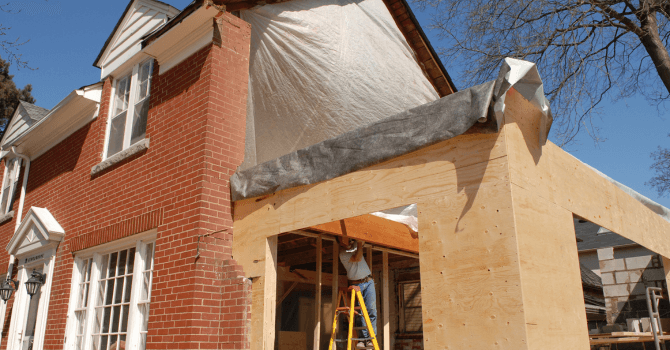 Contractor working on the expansion of a house by adding a new wooden structure.
