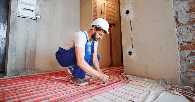 Technician installing heating cables for an underfloor heating system